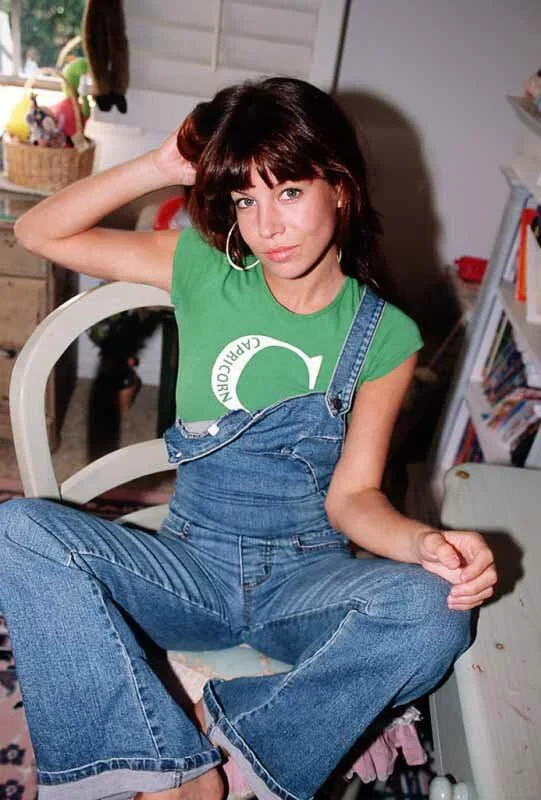 Katie in blue jeans and green top sitting.